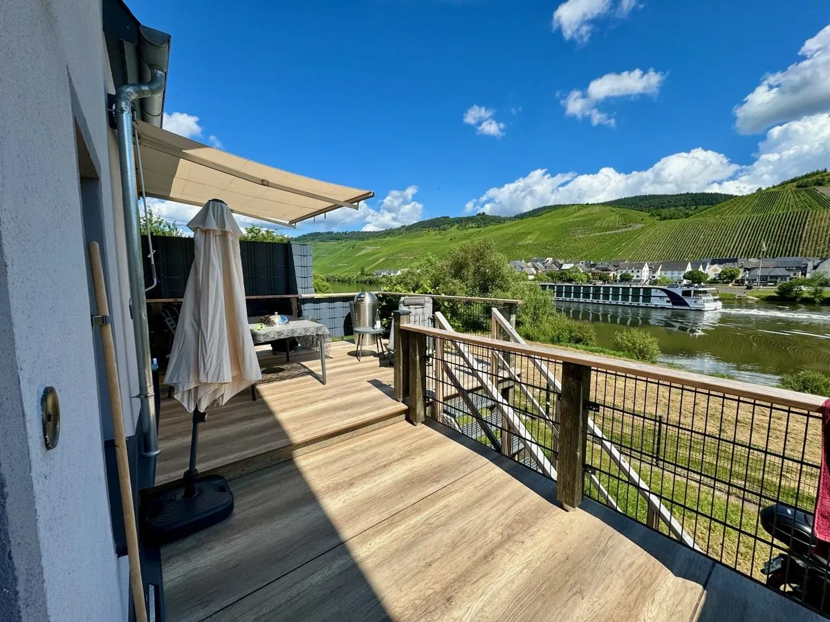 Balkon des Besonderen Moselhauses mit Blick auf Mosel, Weinberge und ein Flussschiff